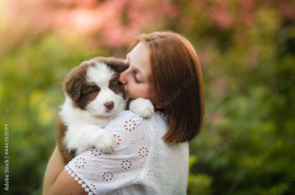 Young white female carrying a lovely border collie puppy in a park Young white female carrying a lovely border collie puppy in a park
