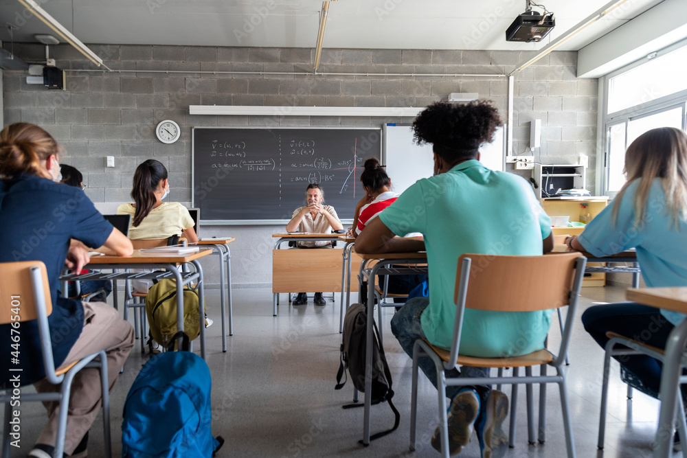 Multiracial group of teen high school students in classroom with mature white male teacher. Copy space. Multiracial group of teen high school students in classroom with mature white male teacher. Copy space.