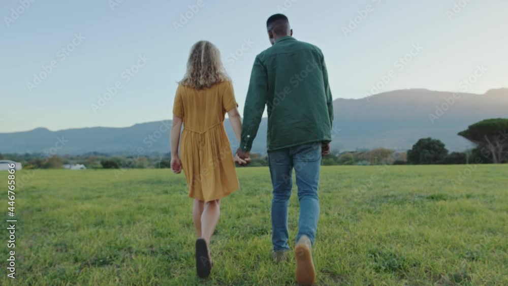 Mixed race romantic couple walking through grass romantically Mixed race romantic couple walking through grass romantically