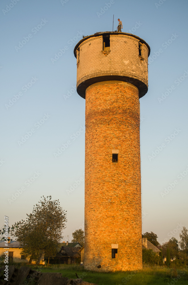 A man stands on an abandoned water tower.