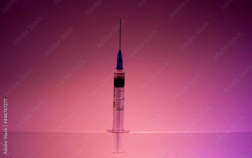 A syringe with an iron needle and medicine is on the table. A syringe with an iron needle and medicine is on the table.