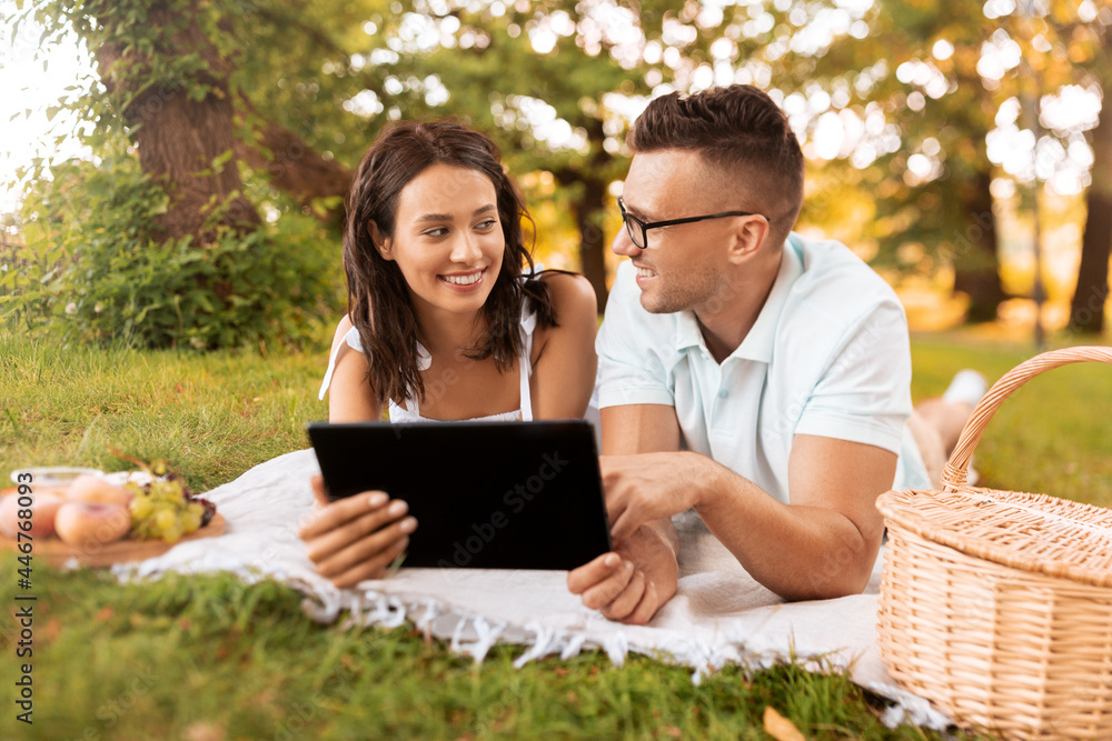 leisure and people concept - happy couple with tablet pc computer having picnic at summer park leisure and people concept - happy couple with tablet pc computer having picnic at summer park