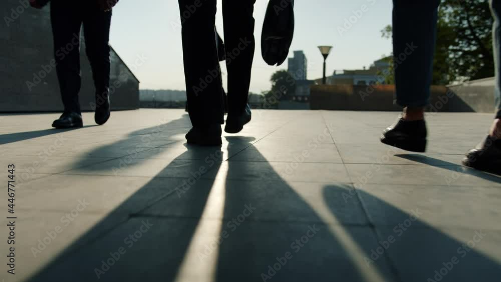 Low angle view of legs in formal trousers and shoes walking outdoors near business center while men and women are going to work. People and city concept. Low angle view of legs in formal trousers and shoes walking outdoors near business center while men and women are going to work. People and city concept.