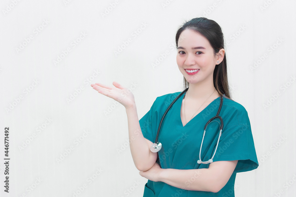Beautiful young Asian woman doctor in a green uniform stands and smiles while pointing to the top on a white background. Beautiful young Asian woman doctor in a green uniform stands and smiles while pointing to the top on a white background.