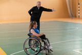 a sports basketball coach explains to a disabled woman in a wheelchair which position to play during a game