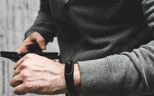 man checks data from fitness bracelet on his smartphone