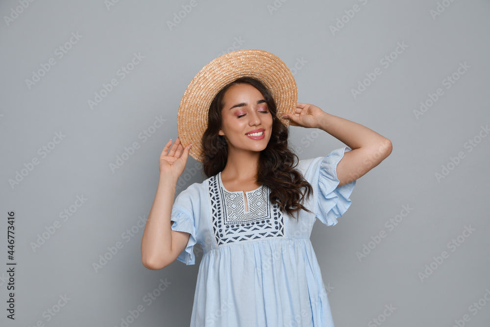 Beautiful young woman with straw hat on light grey background Beautiful young woman with straw hat on light grey background