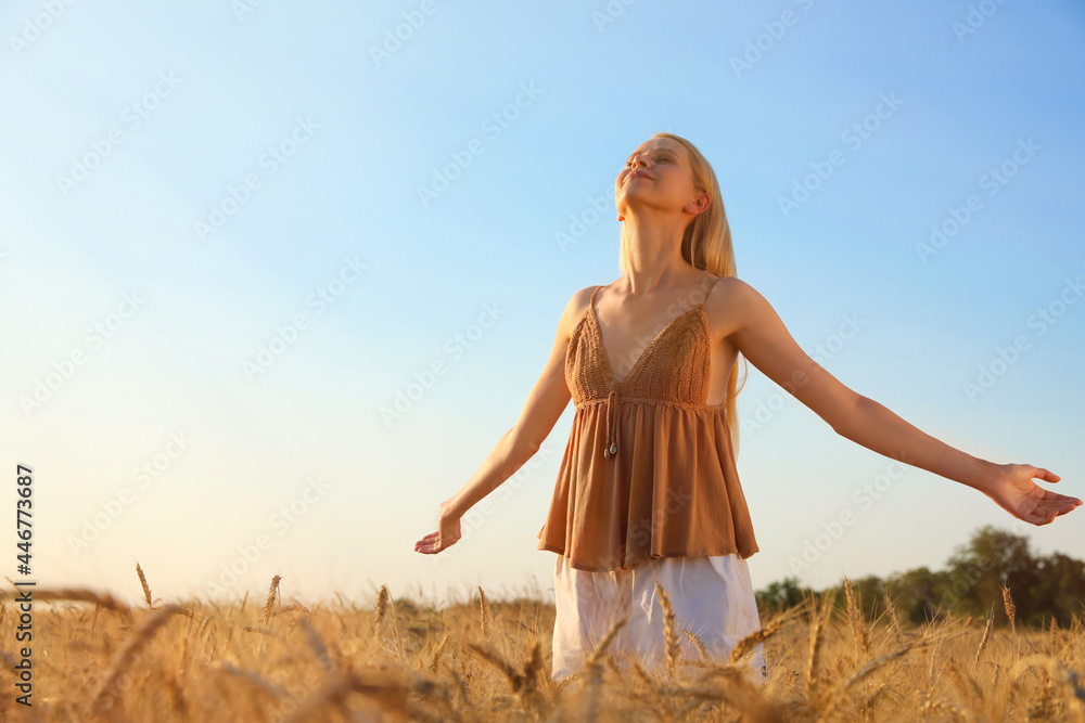 Obraz premium Woman in ripe wheat spikelets field on sunny day