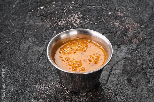 Mustard orange sauce in a metal gravy boat isolated on textured black background. Space for text. High quality photo photo