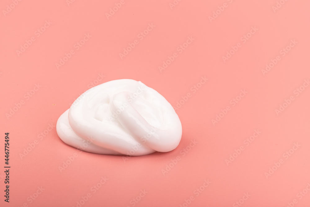 White cosmetic cream smear isolated on pink background. Skincare product creamy texture. White cosmetic cream smear isolated on pink background. Skincare product creamy texture.