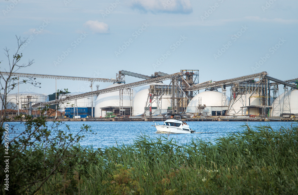 Obraz premium Riga port loading terminal with container ships. Boats and yachts riding on river. Industrial territory meets sustainable environment. 