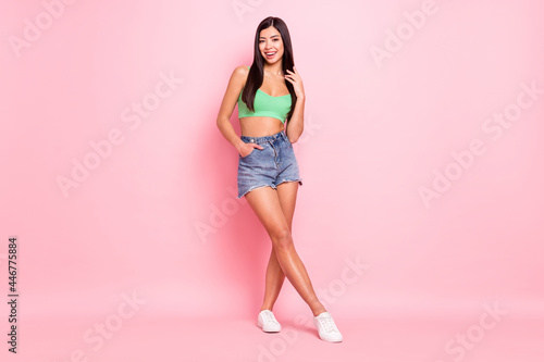 Photo of adorable cute young lady wear green tank-top standing arms pockets smiling isolated pink color background