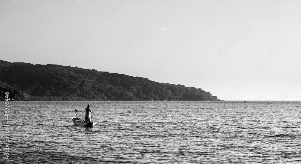 Black and white shot of a fisherman in Belo's beach on sunset - Ilha do Mel, Paraná, Brazil