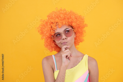 thinking kid in curly clown wig. having fun. thoughtful child wear sunglasses and swimsuit.