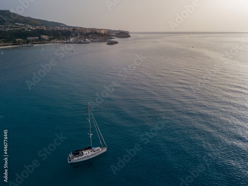 Aerial view of a sailboat moored off the coast of Calabria in Tropea. Italy. Tyrrhenian Sea. Coastline and blue sea 