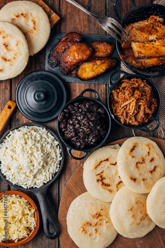 Table served with Venezuelan breakfast, arepas with different types of fillings such as caraotas, carne mechada, pernil , fried plantain and cheese