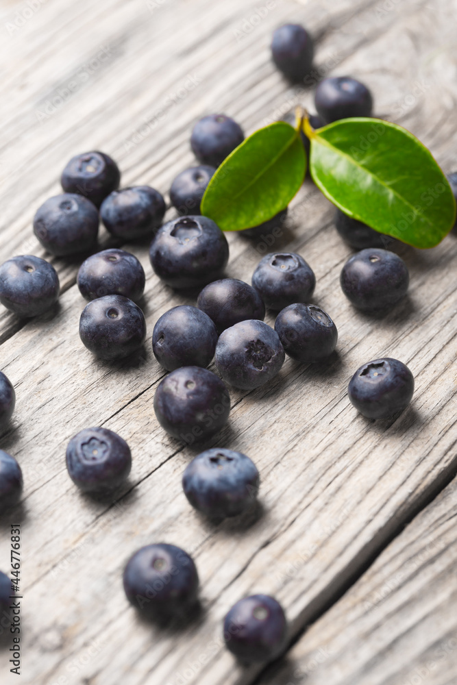 Scattered blueberries on wooden background with leaves