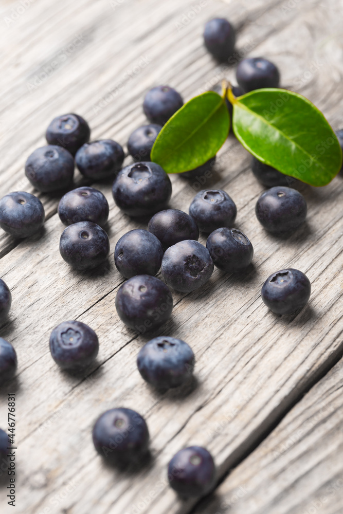Scattered blueberries on wooden background with leaves Scattered blueberries on wooden background with leaves
