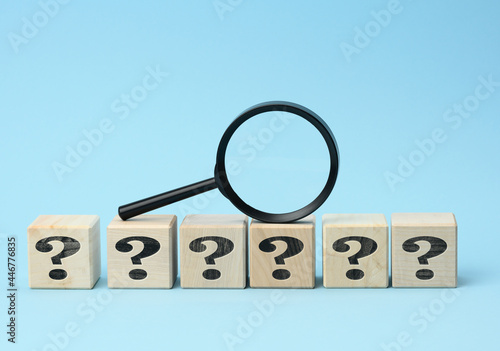 wooden cubes with question marks and a magnifying glass on a blue background