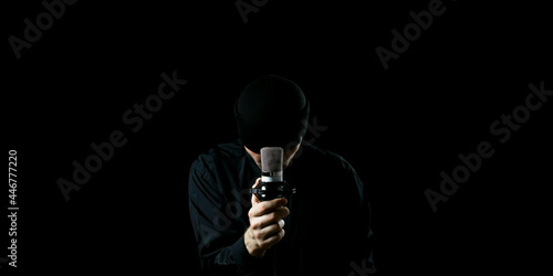 Male musician singing into a microphone. Shot on a black background. Dark atmosphere.