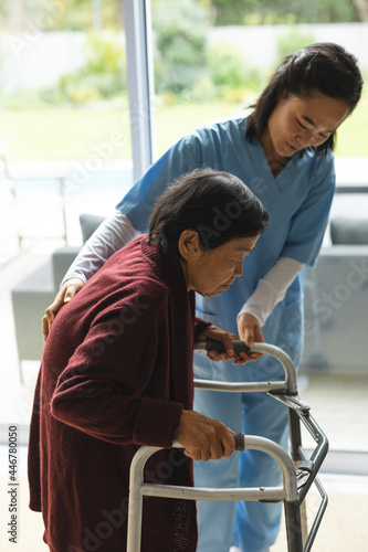 Asian female physiotherapist treating senior female patient at her home