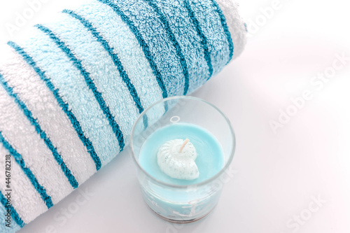 Striped blue soft towel and a candle on a white surface photo