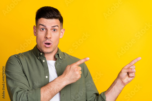 Photo of young man amazed shock indicate fingers empty space advertise suggest isolated over yellow color background