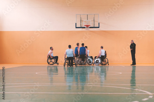 Disabled War veterans mixed race opposing basketball teams in wheelchairs photographed in action while playing an important match in a modern hall. 