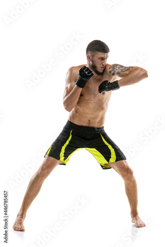 One man, professional male MMA boxer in motion isolated on white studio background. Fit muscular caucasian athlete fighting.