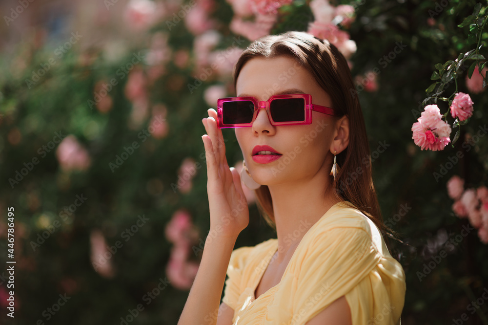 Summer street style, fashion portrait of elegant woman wearing trendy pink frame sunglasses, yellow dress, posing outdoor. Copy, empty space for text Summer street style, fashion portrait of elegant woman wearing trendy pink frame sunglasses, yellow dress, posing outdoor. Copy, empty space for text