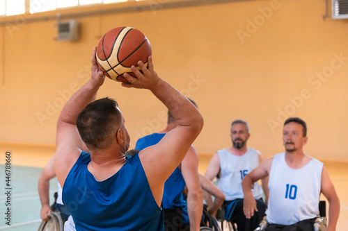 Disabled War veterans mixed race opposing basketball teams in wheelchairs photographed in action while playing an important match in a modern hall.  © .shock