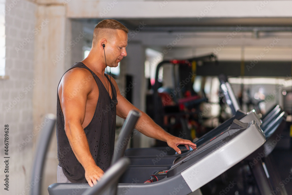 Young man in sportswear running on treadmill at gym.Handsome sport gym man running on the treadmill.Indoors shot. Young man in sportswear running on treadmill at gym.Handsome sport gym man running on the treadmill.Indoors shot.