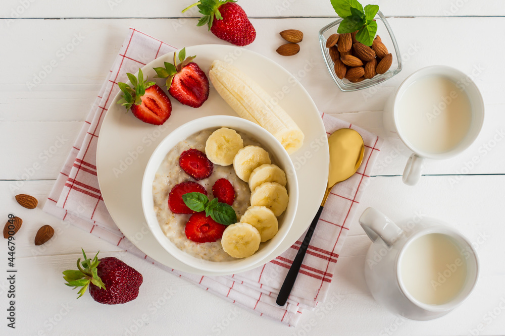 Breakfast. Oatmeal with bananas, strawberries, nuts on the wooden bakground. Healthy breakfast. Close-up. Top view Breakfast. Oatmeal with bananas, strawberries, nuts on the wooden bakground. Healthy breakfast. Close-up. Top view