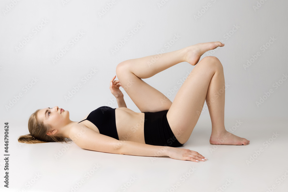 Fototapeta premium Young beautiful adorable girl in black lingerie posing isolated over gray studio background. Natural beauty, spa, cosmetics, fitness and aesthetic cosmetology concept.