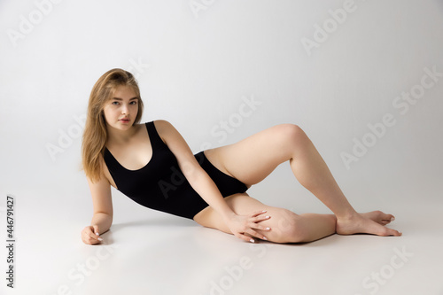 Young beautiful adorable girl in black lingerie posing isolated over gray studio background. Natural beauty, spa, cosmetics, fitness concept.