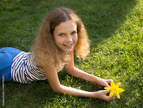 portrait of a beautiful smiling teenage girl 12 years old lying on the grass on a sunny summer day. enjoyment of vacations, relaxation, dreams. Joyful summer, happy childhood, good mood photo