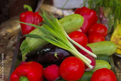 Various products are offered at a street food fair, event, festival. Green onion feathers, red tomatoes, blue eggplants, green courgettes, red bell peppers, and other foods.