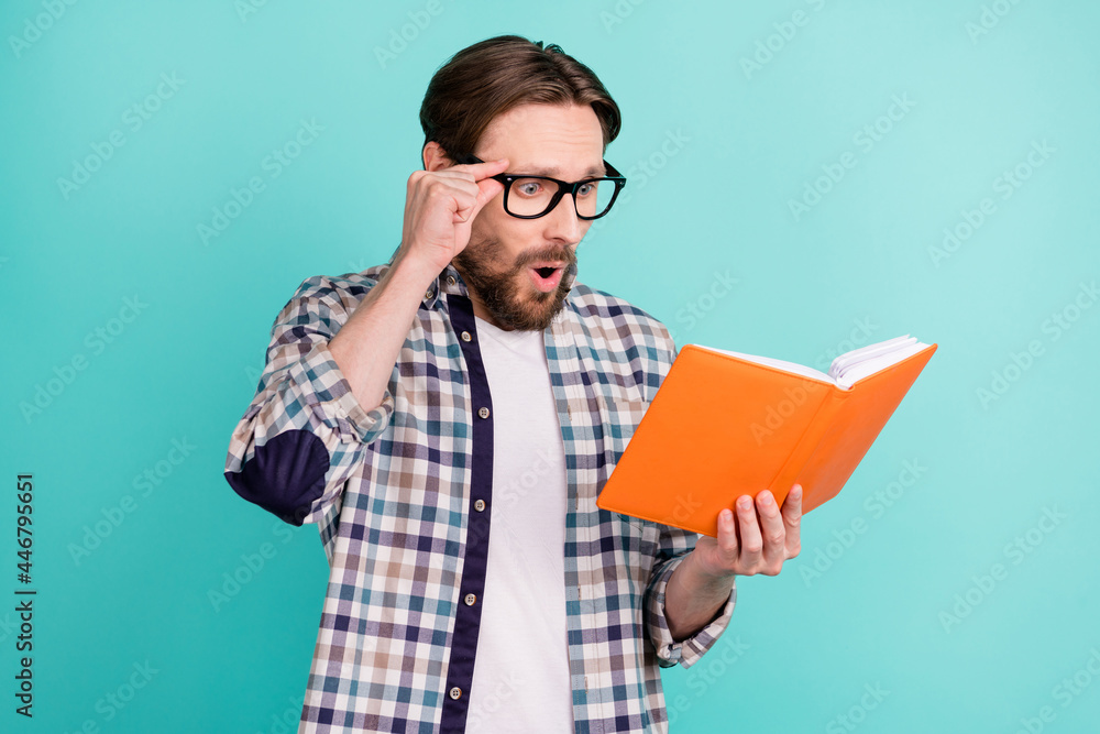 Profile side photo of young man amazed shocked surprised read book fake novelty isolated over teal color background Profile side photo of young man amazed shocked surprised read book fake novelty isolated over teal color background
