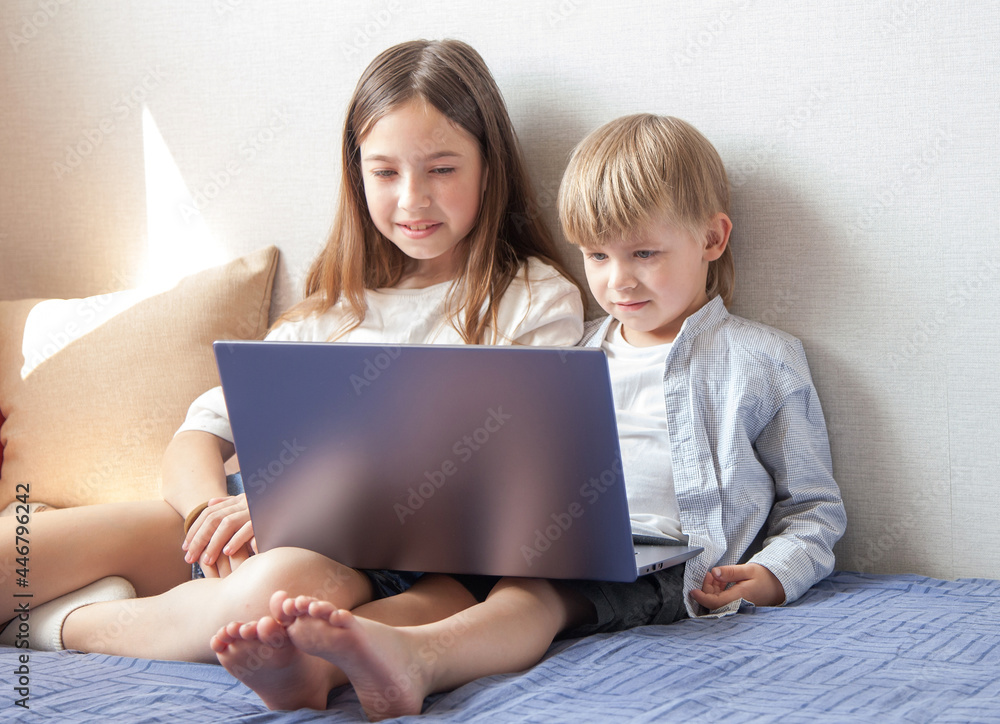 Siblings look at the laptop screen Siblings look at the laptop screen