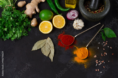 Concept, fresh herbs, ginger, lemon, lime, paprika, curry, spice mortar, top view, on a dark table, horizontal, no people,
