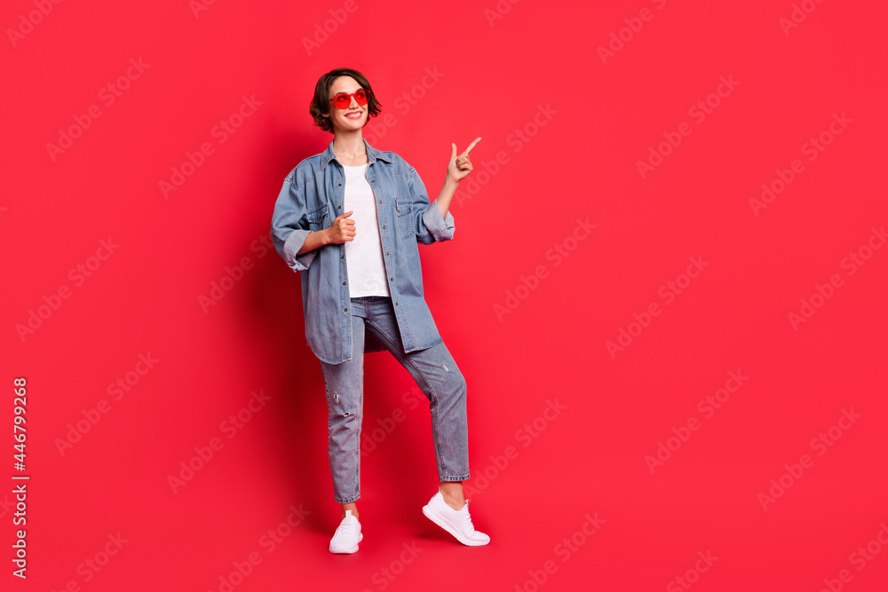 Full length body size photo girl wearing sunglass pointing copyspace recommending isolated vibrant red color background Full length body size photo girl wearing sunglass pointing copyspace recommending isolated vibrant red color background