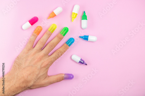 Male hand colorful nails, different colours on pink background. Diversity concept, LGBT icon, togetherness, freedom of choice.