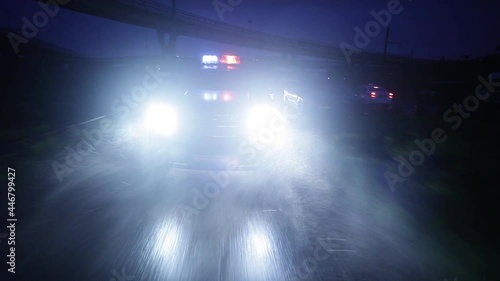 A black police car is driving fast at night with flashing lights. photo