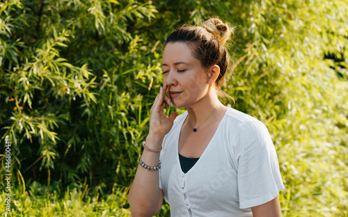 Photography Young woman professional yogi practicing yoga asana alternate breathing through the nostrils outdoors, close-up