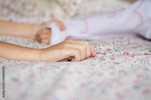 The child's hand lies on the bed on a light background.