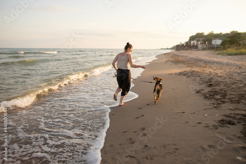 young woman with a beagle dog having fun by the sea