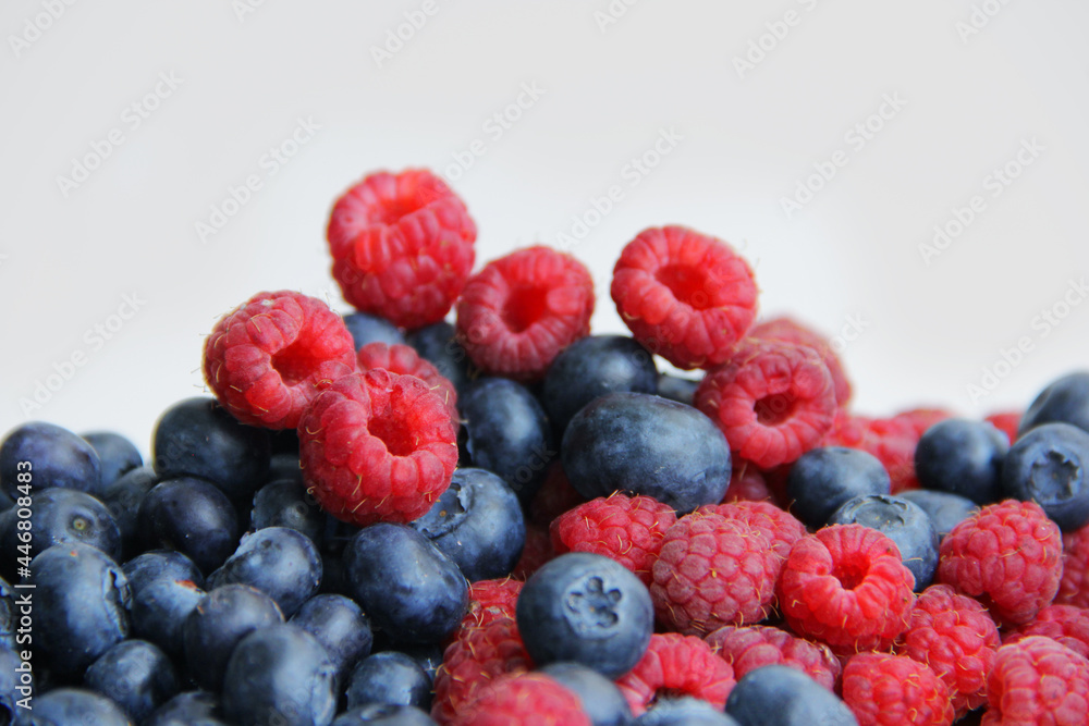 fresh raspberries and blueberries on a white background close-up fresh raspberries and blueberries on a white background close-up
