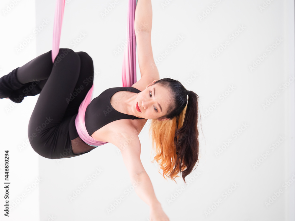 Young beautiful Asian dancer dressed in black color performing aerial dance with multi-color fabrics in the studio.. Young beautiful Asian dancer dressed in black color performing aerial dance with multi-color fabrics in the studio..