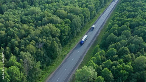 A long truck and a semi-truck follow each other to their destination. Cargo. The highway is laid through the picturesque countryside. Dense trees, forest. High quality. 4k footage.