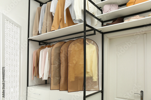 Garment bags with clothes on rack in dressing room